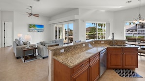 A spacious kitchen with granite countertops, wooden cabinets, and a built-in dishwasher.