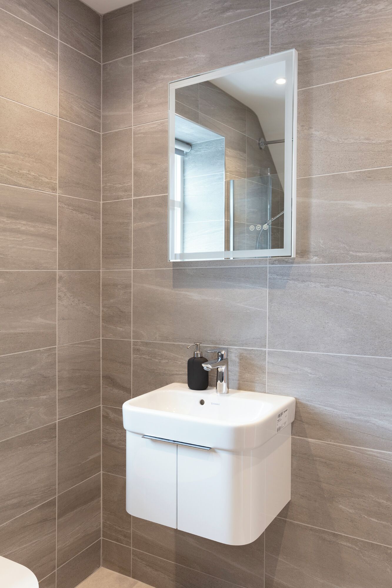 Une salle de bain avec un lavabo blanc, un miroir et un espace douche.