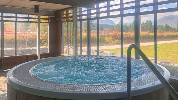 Un jacuzzi con vista a un paisaje natural a través de amplios ventanales.