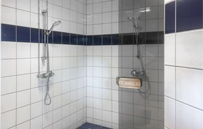 Un espacio de ducha con paredes de azulejos y un estante de madera.