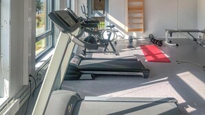 Un gimnasio con cintas de correr, una bicicleta estática y un banco para pesas.