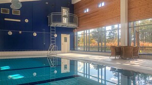 Una piscina interior con un deck de madera y ventanas amplias.