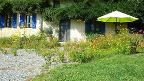 Ein Haus mit Garten, einem Kiesweg und einem grünen Sonnenschirm.