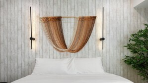 Una cama con ropa blanca, una pared de madera con tablones verticales y dos lámparas fijadas a la pared.