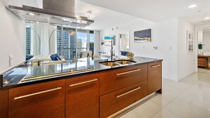 A modern kitchen with a large island, stainless steel appliances, and a view of the cityscape.