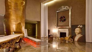 Un hall d’entrée luxueux, agrémenté d’une grande sculpture dorée, d’une cheminée et d’œuvres d’art classiques.