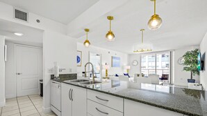 A modern kitchen with white cabinets, granite countertops, and gold pendant lights. - The Club 3904 · High Floor Unit Located in Brickell - Free Parking (Miami)
