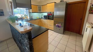 Eine moderne Küche mit Kochinsel, integriertem Backofen und Edelstahl-Kühlschrank.