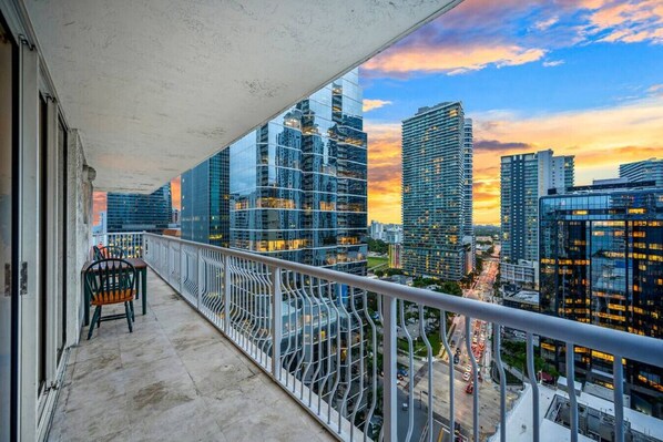 A balcony with a view of modern high-rise buildings during sunset.