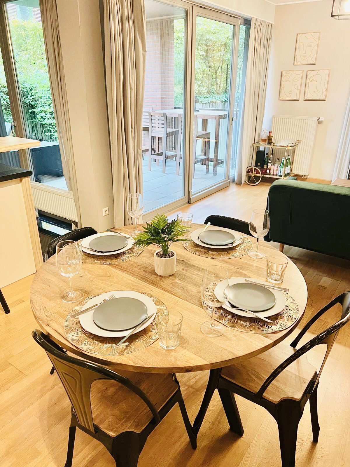 Un comedor con una mesa redonda de madera dispuesta para cuatro personas, rodeada de sillas.