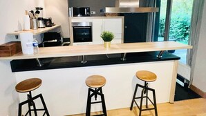 A modern kitchen with a central island, bar stools, and a view of greenery outside. - Chic one bedroom with parking&terrace (Luxembourg City)