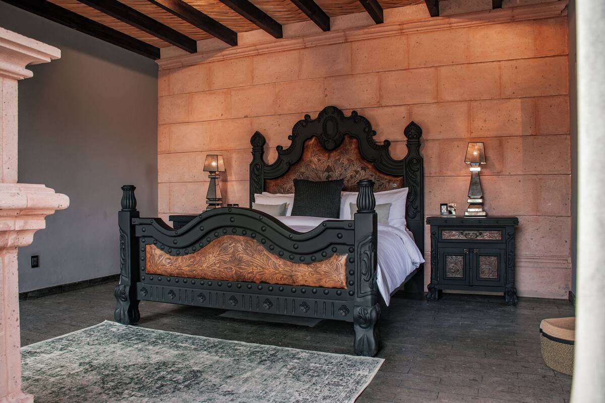 Un dormitorio con una cama grande, dos mesitas de noche y una alfombra tejida.