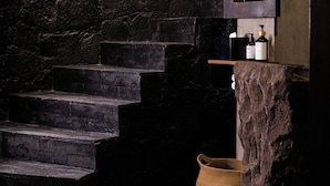 A stone staircase leading to a bathroom with a mirror, toiletries, and a woven basket. - Casa Nueve (San Miguel de Allende)