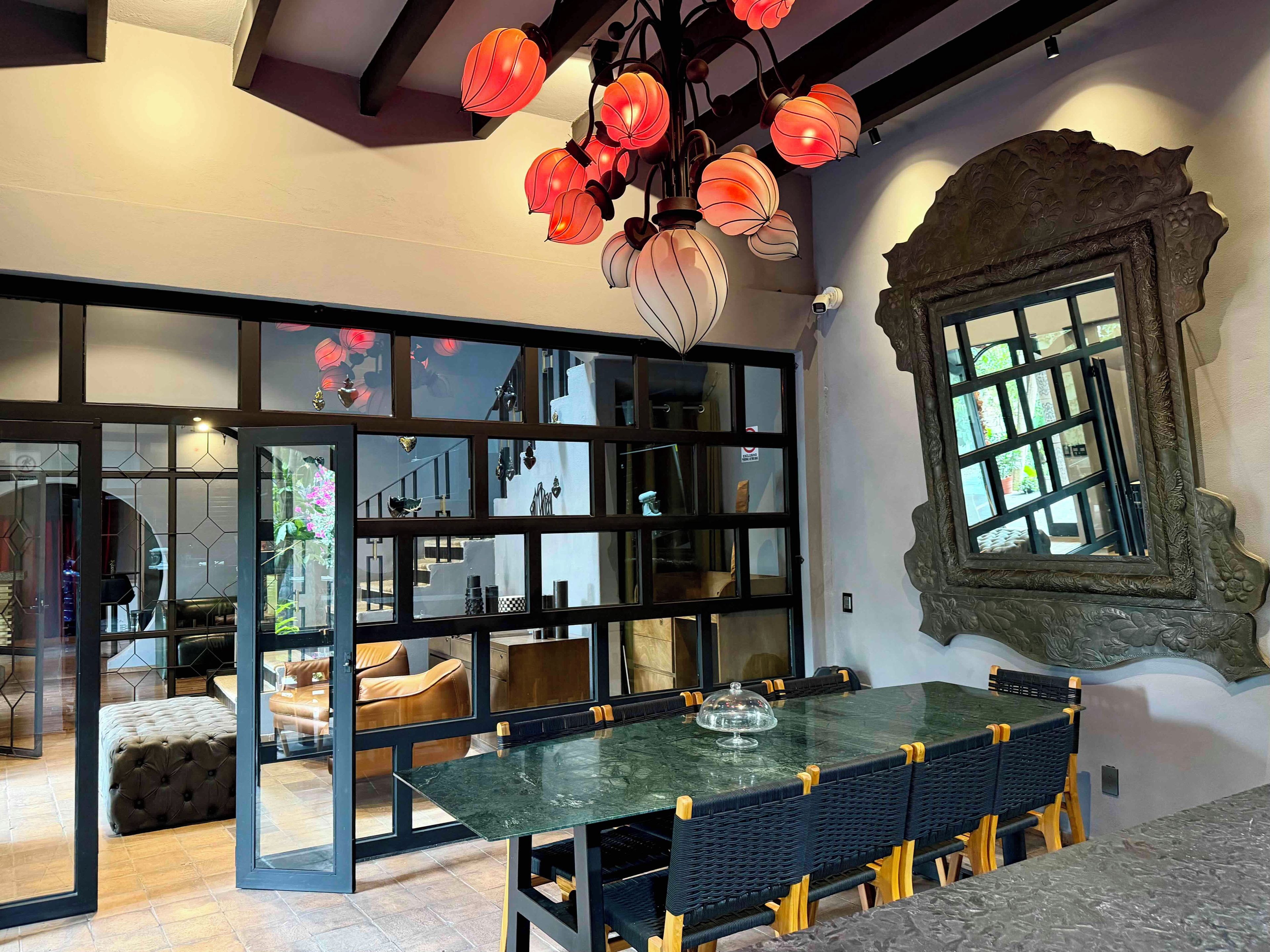 A dining area with a glass partition, a table with chairs, and a decorative ceiling light fixture.