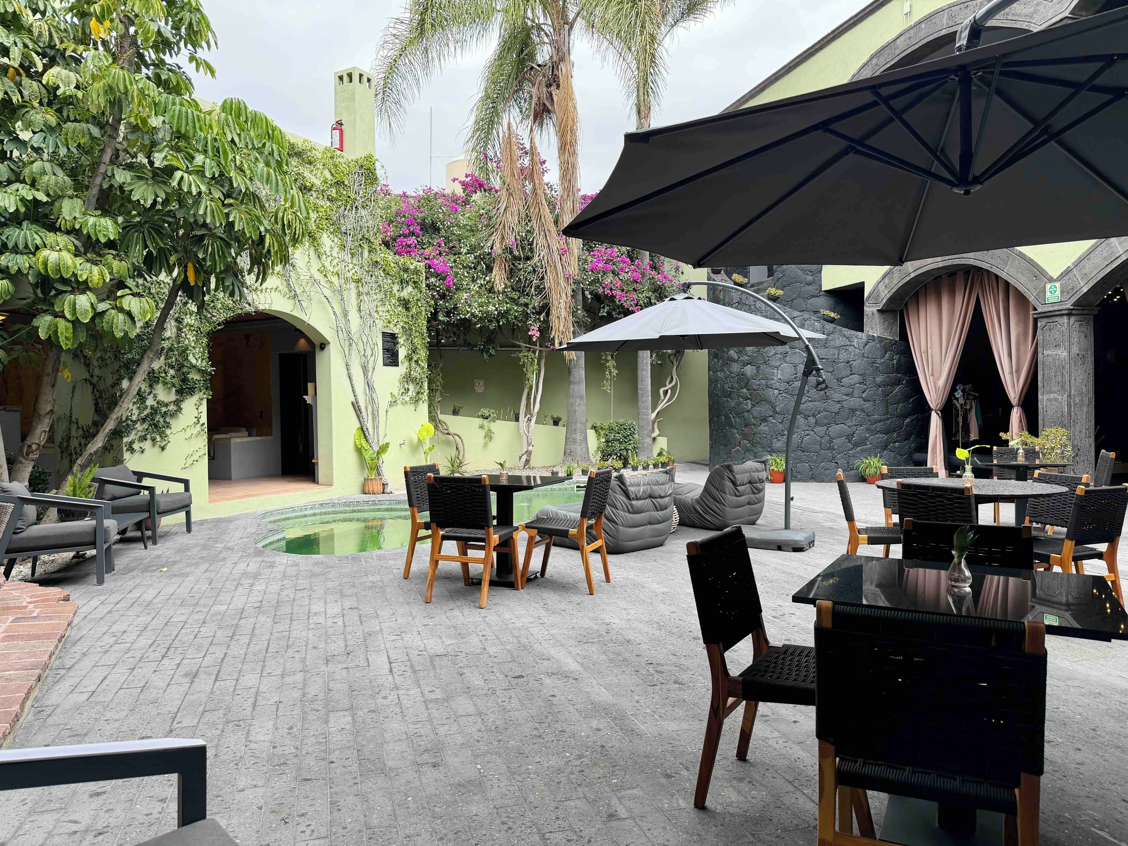 Un patio exterior con mobiliario, una piscina y una zona cubierta con mesa y sillas.