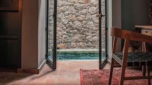 A room with a stone wall, a wooden chair, and a tiled floor. - Casa Nueve (San Miguel de Allende)