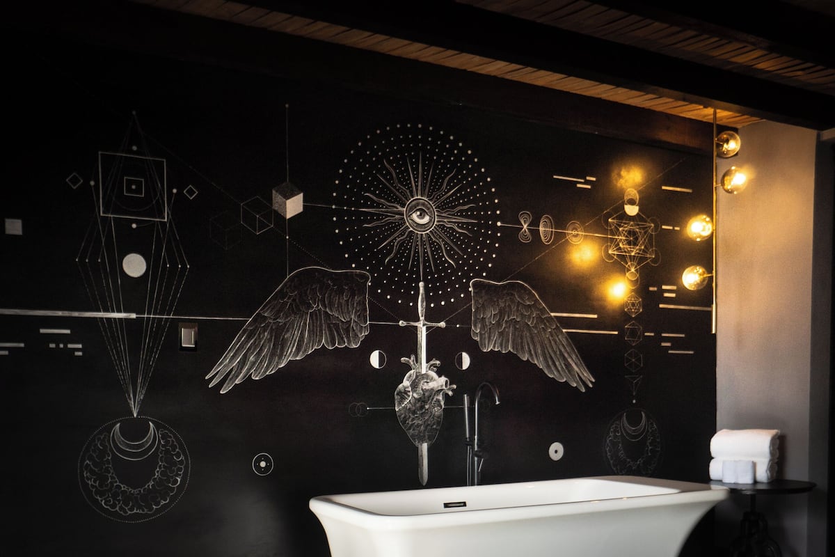 Un baño moderno con una bañera independiente, un mural en la pared y suelo estampado.