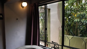 A modern bathroom with a freestanding bathtub, large windows, and a view of greenery outside. - Casa Nueve (San Miguel de Allende)