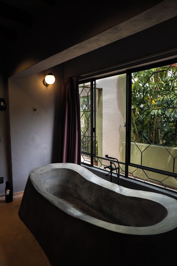 Ein modernes Badezimmer mit einer freistehenden Badewanne, großen Fenstern und Blick auf Grünfläche.