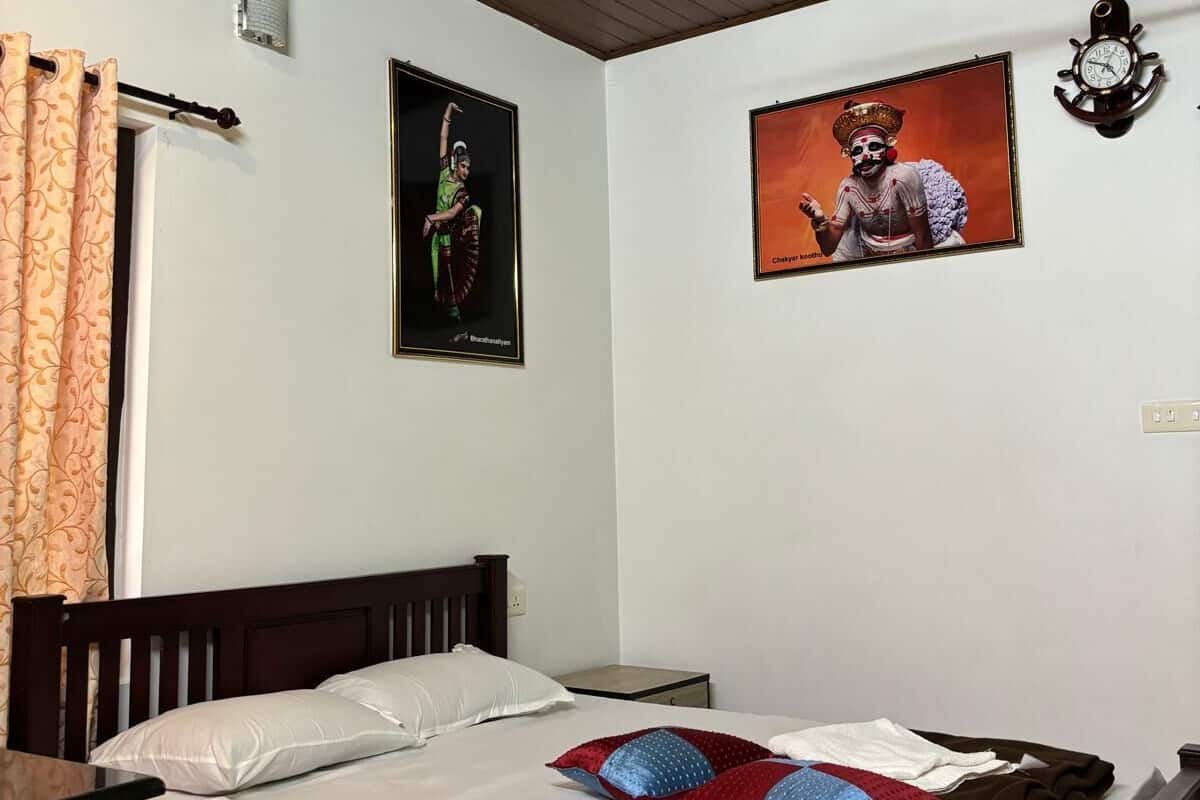 A bedroom with a wooden bed, white bedding, a ceiling fan, and two wall-mounted clocks.