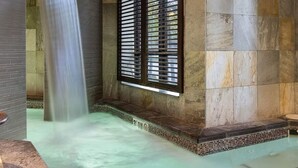 Un área de spa con un jacuzzi, una cascada y una ventana con persianas.