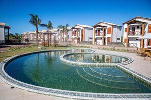 Ein Resort mit einem zentralen Schwimmbad, mehreren Gästehäusern und einer gepflegten Rasenfläche.