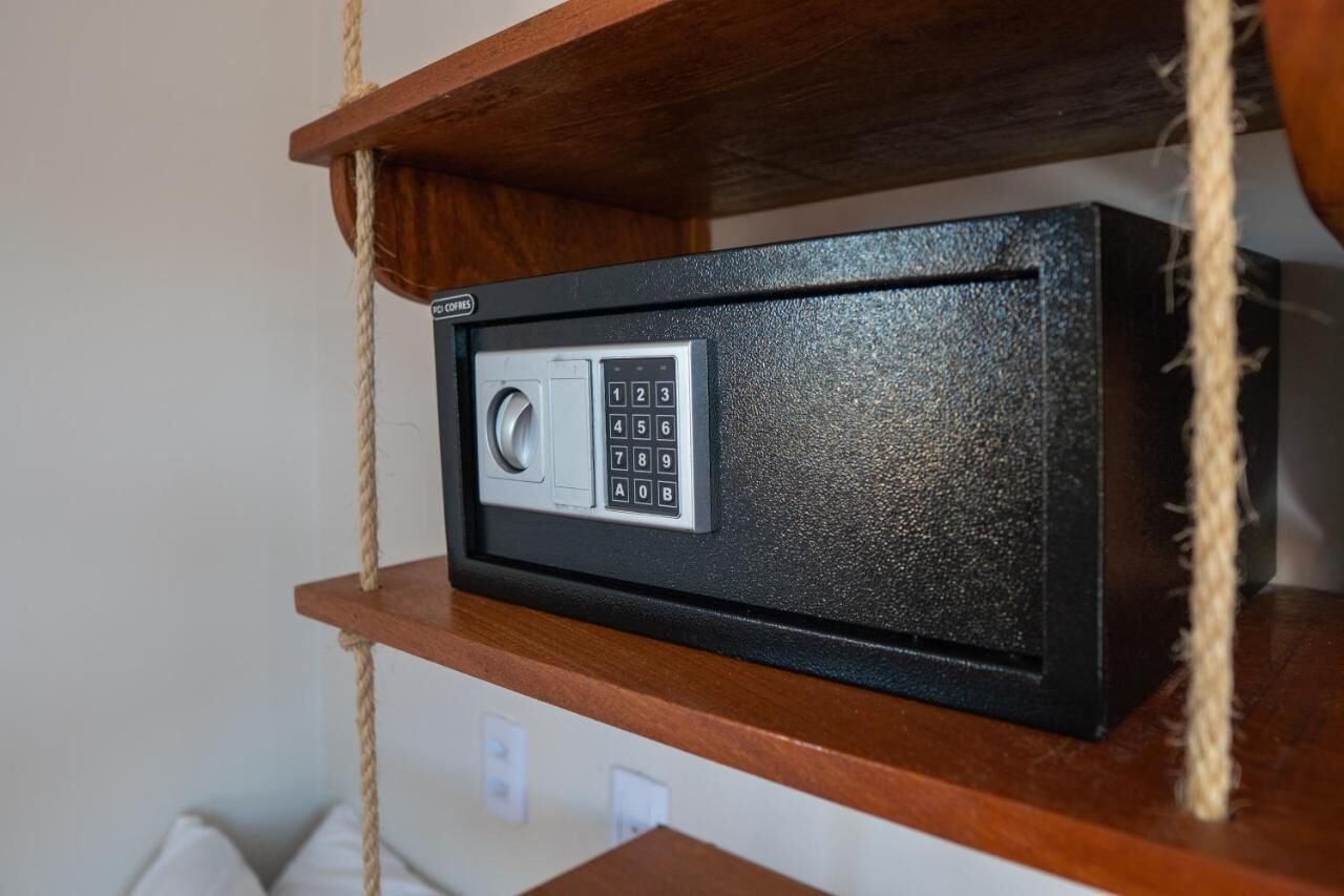 A safe with a keypad on a wooden shelf.