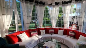 A cozy seating area with a curved sofa, a glass coffee table, and sheer curtains.