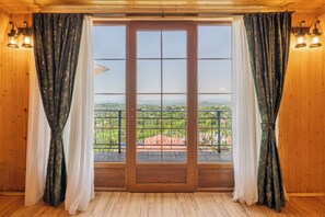 A wooden room with a large sliding glass door leading to a balcony with a metal railing. - Roots Resort (Kobuleti)