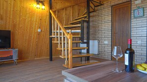 A wooden interior with a spiral staircase, a wine bottle, and a glass on a table.