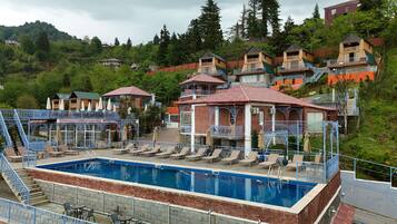A pool area with lounge chairs and a swimming pool, surrounded by buildings with balconies and stairs.