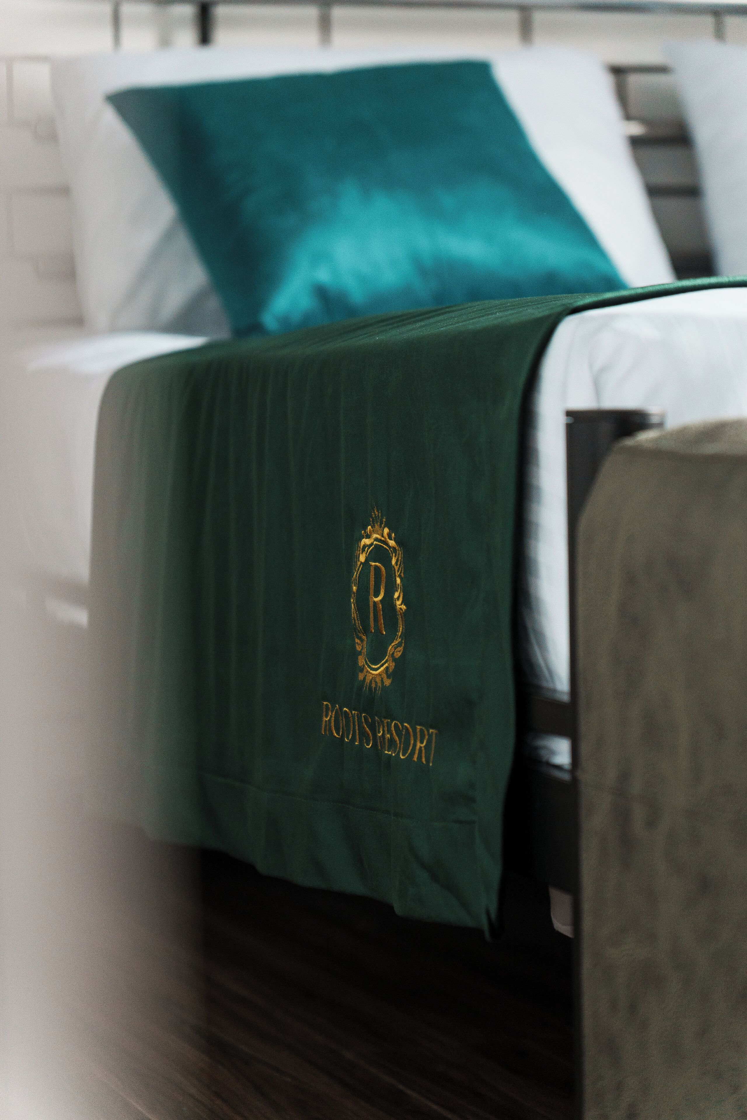 A bed with a green bedspread featuring a gold emblem and the text "PODIS RESORT".