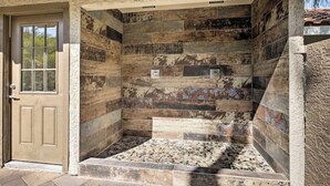 Eine Dusche mit Steinwänden, gefliestem Boden und einer Tür links.