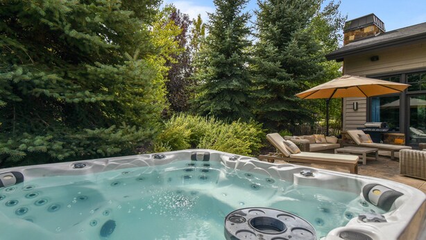 Un bain à remous entouré d’une végétation luxuriante et agr émenté de mobilier d’extérieur.