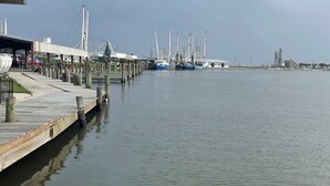 A waterfront dock with boats, a pier, and a bridge in the background.