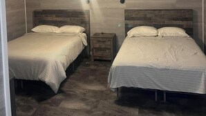 A room with two beds, a ceiling fan, and a nightstand.