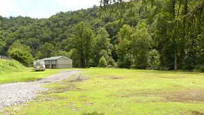 Une propriété située en zone rurale, avec une allée en gravier menant à une maison et à une caravane.