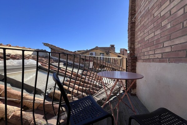 A balcony with a metal railing, a small round table, and two chairs.