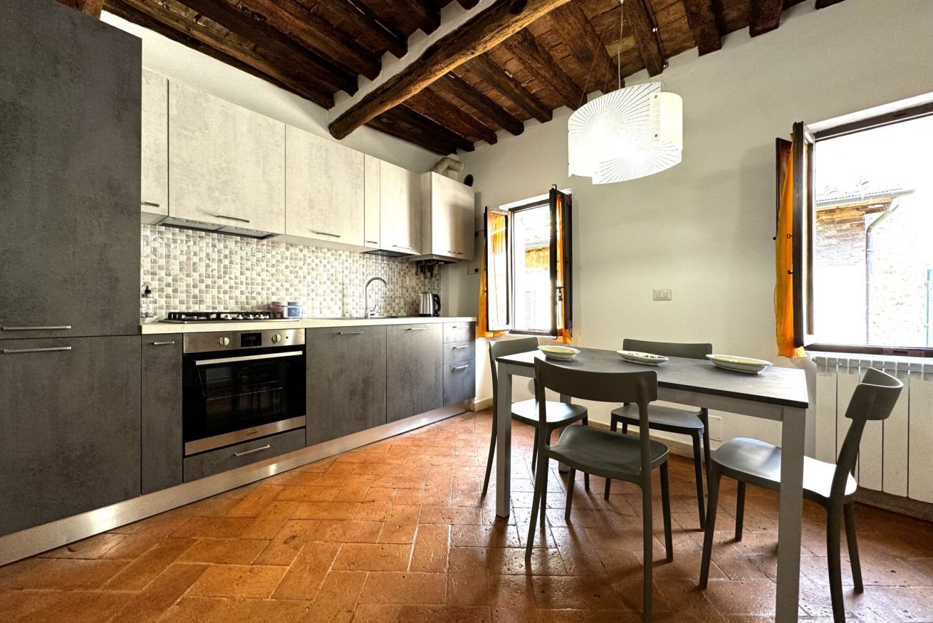 A kitchen with grey cabinets, a tiled backsplash, and a wooden floor.