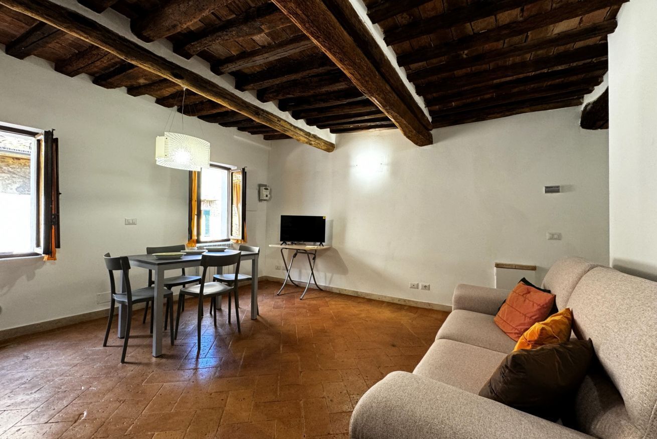 A living room with a sofa, a dining table with chairs, a TV on a stand, and a fireplace.