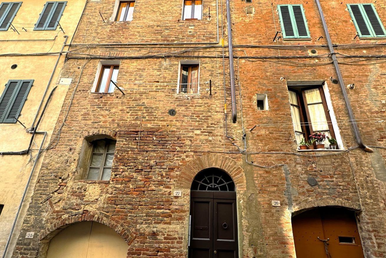 A multi-story brick building with arched doorways and windows with shutters.