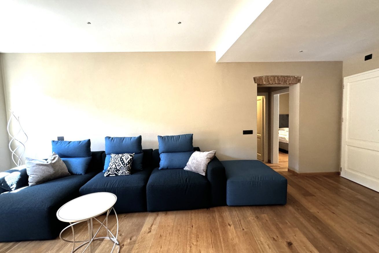 Un salon moderne avec un canapé d’angle, une petite table ronde et un plancher en bois.