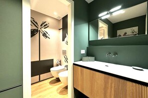 A modern bathroom with a wooden vanity, a toilet, and a wall-mounted mirror.