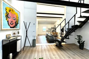 A modern interior with a staircase, a living area with a sofa, and a dining area.