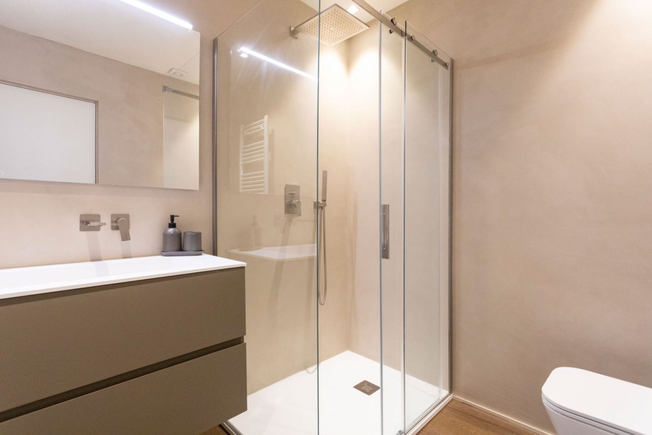 Une salle de bain moderne avec une douche à parois de verre, un lavabo blanc et des toilettes.