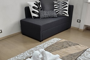 A modern living room with a sofa, patterned cushions, and a decorative rug.