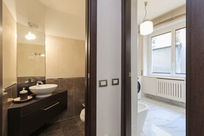 A modern bathroom with a large mirror, a white sink, and a toilet. - Explore Milan with your family from this spacious and cozy apartment, located just a 15-minute walk from the Duomo! Ideal for families of up to 5 people (plus a crib available upon request), the apartment is equipped with all the comforts you need for a  (Milan)