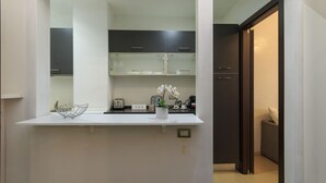 A modern kitchen with white countertops, a coffee machine, and a small plant. - Explore Milan with your family from this spacious and cozy apartment, located just a 15-minute walk from the Duomo! Ideal for families of up to 5 people (plus a crib available upon request), the apartment is equipped with all the comforts you need for a  (Milan)