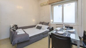 A modern room with a bed, a dining table, and a window. - Explore Milan with your family from this spacious and cozy apartment, located just a 15-minute walk from the Duomo! Ideal for families of up to 5 people (plus a crib available upon request), the apartment is equipped with all the comforts you need for a  (Milan)
