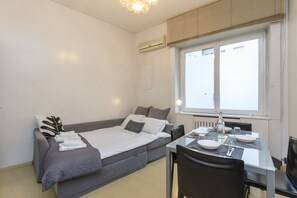 A modern room with a bed, a dining table, and a window. - Explore Milan with your family from this spacious and cozy apartment, located just a 15-minute walk from the Duomo! Ideal for families of up to 5 people (plus a crib available upon request), the apartment is equipped with all the comforts you need for a  (Milan)
